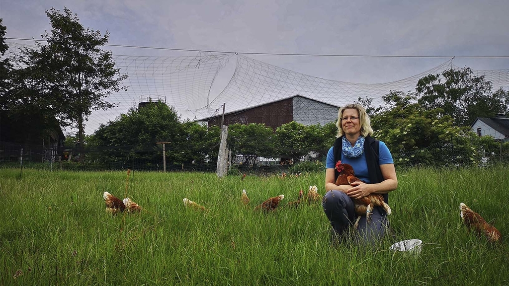 Vergrößerung des Bildes für Landwirtin Ina Fischer mit Hühnern auf dem Rasen.
