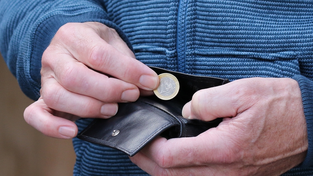 Vergrößerung des Bildes für Detailfoto zeigt Männerhände, die einen Euro aus einem Portemonaie nehmen.