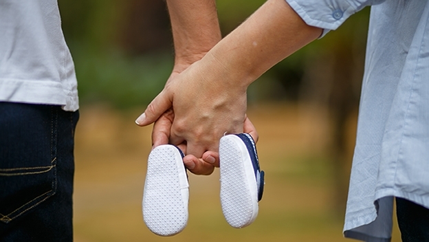 Vergrößerung des Bildes für Ein Mann und eine Frau mit Babyschuhen in den Händen.