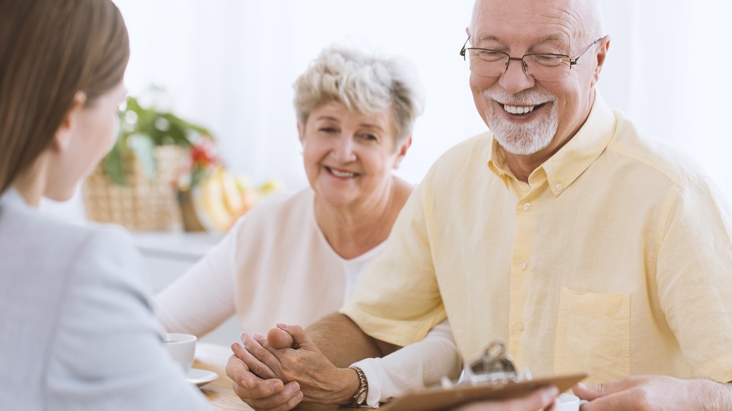 Vergrößerung des Bildes für Senioren bei der Pflegeberatung. Beraterin zeigt dem Ehepaar ein Formular. .