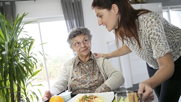 Vergrößerung des Bildes für Pflegekraft mit Seniorin beim Essen.
