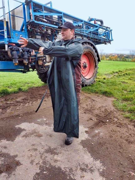 Vergrößerung des Bildes für Bild: Mann vor Landmaschine beim Anziehen einer Ärmelschürze.