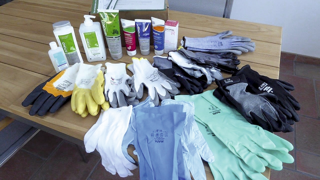 Vergrößerung des Bildes für Hautschutzprodukte und Handschuhe auf einem Tisch.